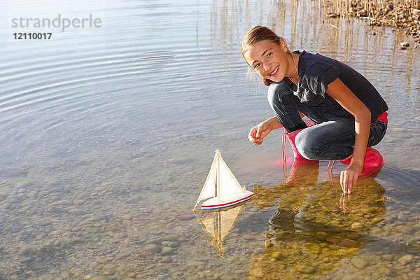 Junges Mädchen schwimmt Spielzeugboot auf dem Wasser