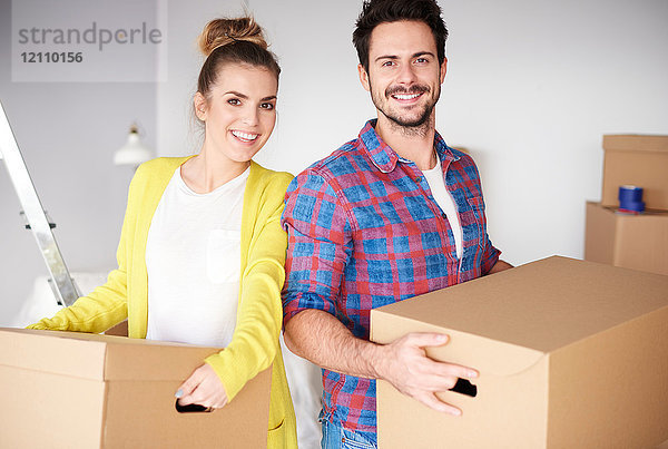 Junges Paar zieht nach Hause  hält Kartons in der Hand und lächelt