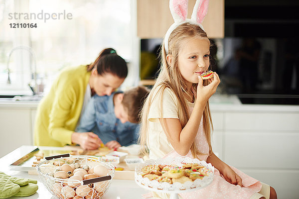 Mädchen isst Osterkekse auf der Küchentheke