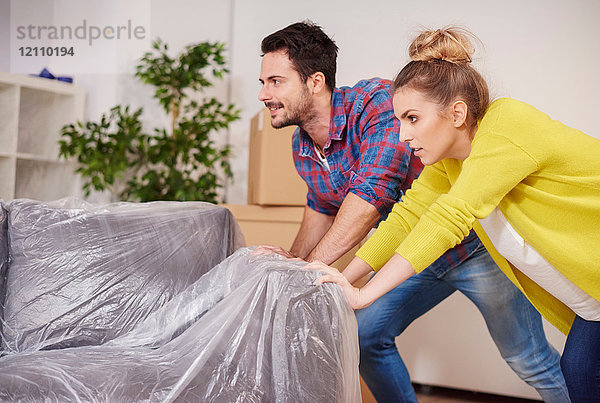 Junges Paar in neuer Wohnung  das Möbel umräumt