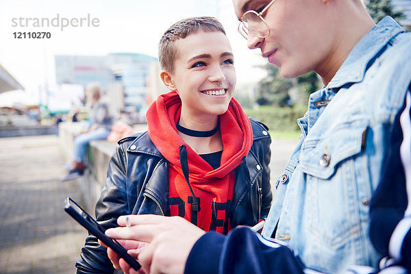 Junges Paar betrachtet Smartphone in der Stadt