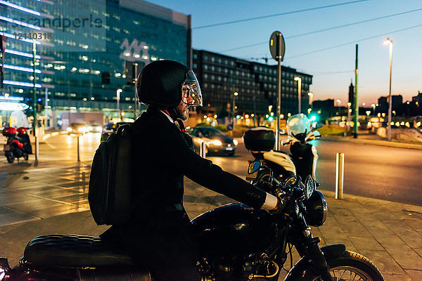 Reifer Geschäftsmann nachts im Freien  Motorrad fahren