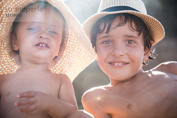 Porträt eines Jungen und eines kleinen Bruders am Strand mit Sonnenhüten  Begur  Katalonien  Spanien