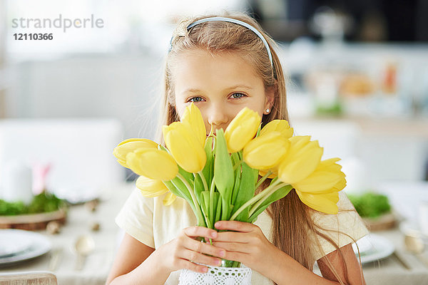 Porträt eines Mädchens  das sich hinter gelben Tulpen hält und versteckt