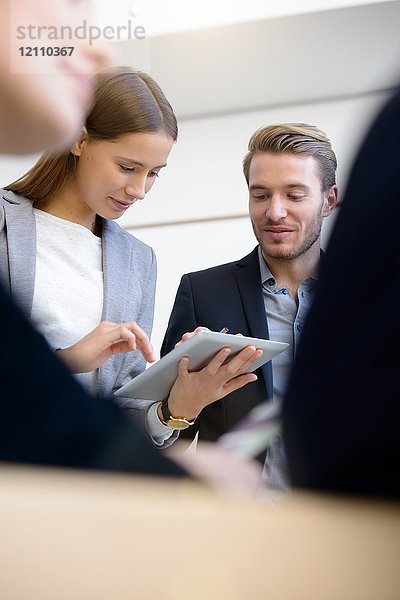 Junge Geschäftsfrau und Mann benutzen digitalen Tablet-Touchscreen am Konferenztisch