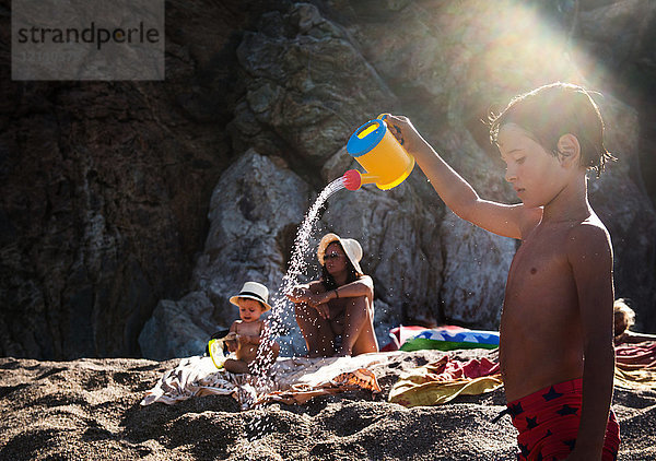 Junge am Strand besprüht Spielzeuggießkanne  Begur  Katalonien  Spanien