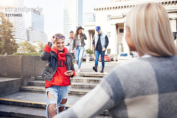 Zwei junge Freundinnen begrüßen sich in der Stadt