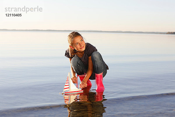 Junges Mädchen schwimmt Spielzeugboot auf dem Wasser