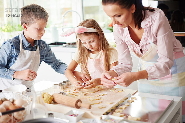 Mädchen  Bruder und Mutter backen Osterkekse an der Küchentheke