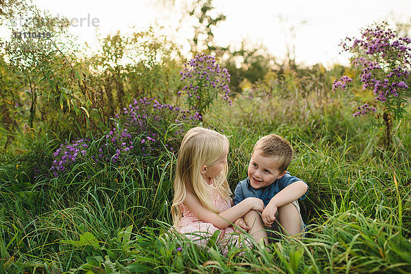 Junge und Mädchen sitzen zusammen im hohen Gras