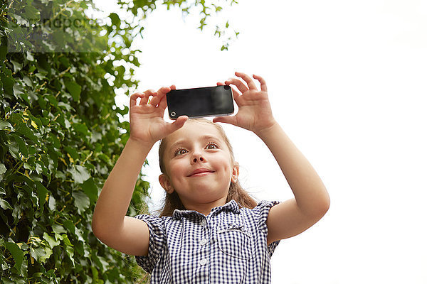 Junges Mädchen  im Freien  Fotografieren mit Smartphone  Blick aus niedrigem Winkel