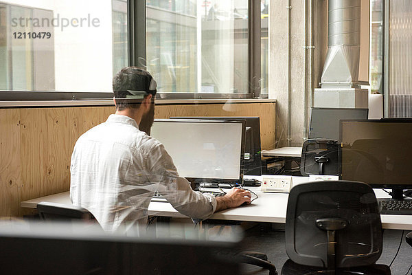 Rückansicht eines Mannes im Büro mit einem Desktop-Computer