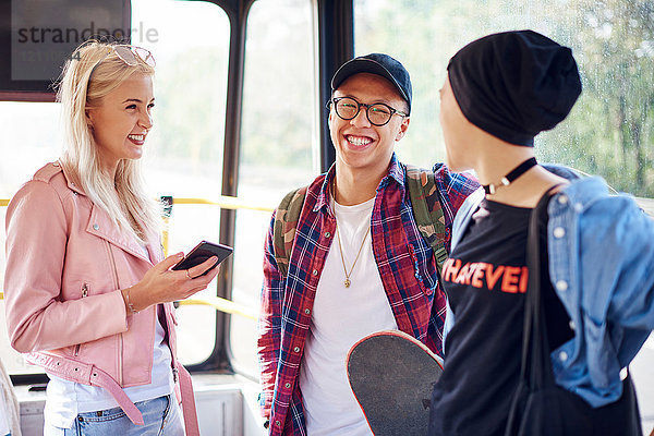 Drei junge erwachsene Freunde unterhalten sich in der Stadtbahn