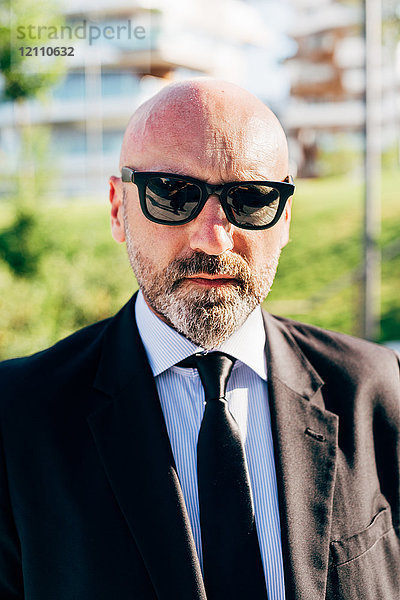 Porträt eines reifen Geschäftsmannes im Freien  der eine Sonnenbrille trägt