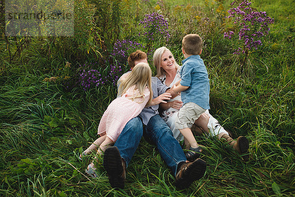 Eltern und Kinder liegen gemeinsam im hohen Gras