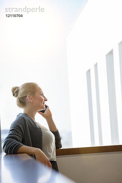 Junge Geschäftsfrau telefoniert mit Smartphone im Bürokorridor