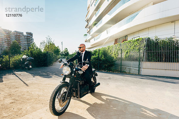 Porträt eines reifen Geschäftsmannes im Freien  auf einem Motorrad sitzend