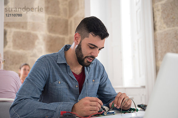 Junger männlicher Computertechniker repariert Kabel auf Bürotisch