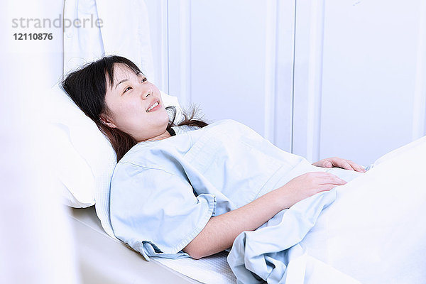 Schwangere Frau im Krankenhausbett liegend