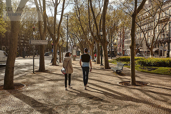 Paar zu Fuß auf baumgesäumter Straße  Lissabon  Portugal