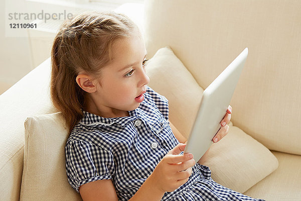 Junges Mädchen  entspannt auf dem Sofa  mit digitalem Tablet