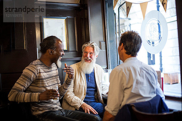Drei reife Männer  die zusammen in der Kneipe sitzen und sich unterhalten