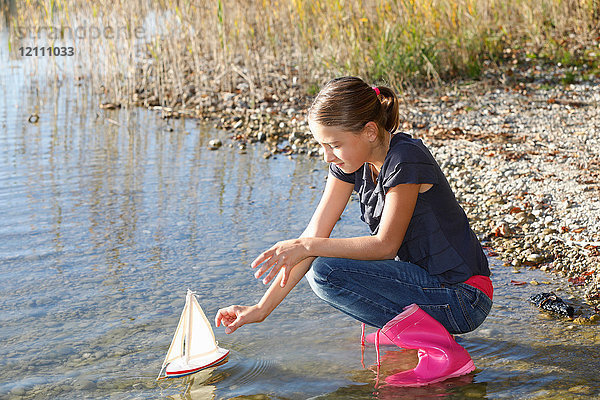 Junges Mädchen schwimmt Spielzeugboot auf dem Wasser