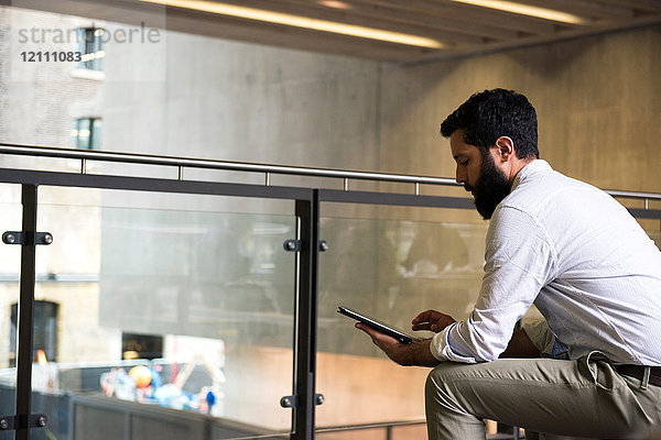 Mann im Zwischengeschoss eines Bürogebäudes mit digitalem Tablet