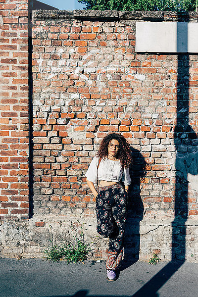 Frau posiert gegen Ziegelmauer