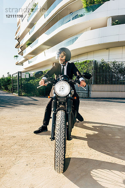 Porträt eines reifen Geschäftsmannes im Freien  auf Motorrad sitzend  Motorradhelm tragend