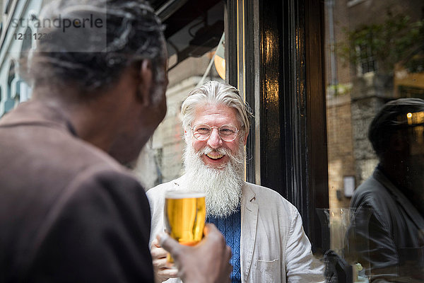 Zwei reife Männer  die vor der Kneipe stehen und Bier trinken