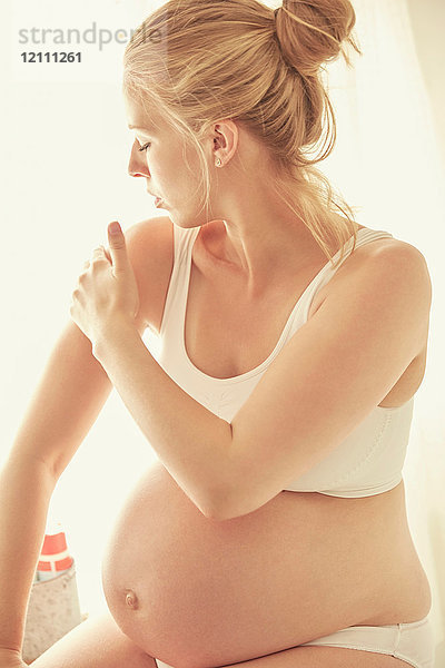 Schwangere Frau trägt Feuchtigkeitscreme auf