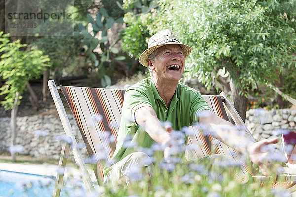 Mann im Garten sitzt lachend im Liegestuhl