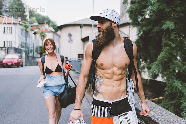 Junges Paar in Badebekleidung und Rucksäcken beim Spaziergang in Como  Lombardei  Italien