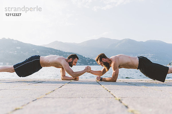 Zwei junge Männer machen Push-Ups am Wasser  Comer See  Lombardei  Italien