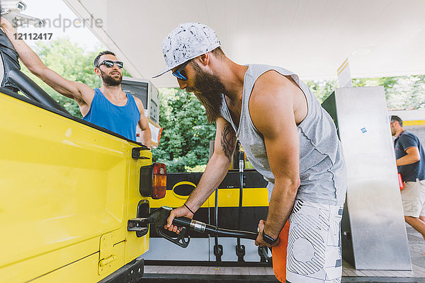 Junger männlicher Hipster beim Tanken eines Geländewagens an einer Tankstelle auf Autoreise  Como  Lombardei  Italien