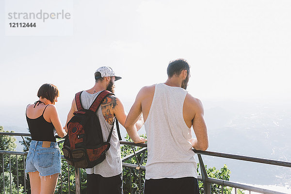 Drei junge Hipster-Freunde schauen vom Balkon auf den Comer See  Como  Lombardei  Italien