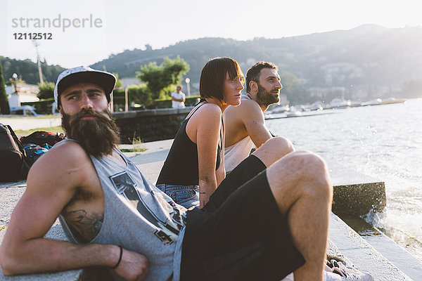Drei junge Hipster sitzen mit Blick auf den Comer See  Como  Lombardei  Italien
