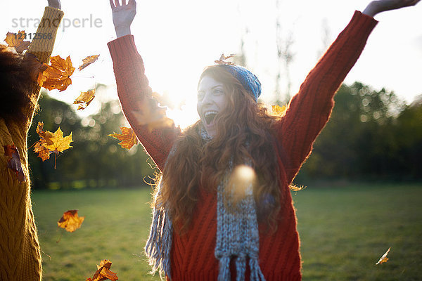 Freunde werfen Herbstblätter in die Luft