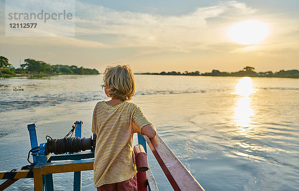Junge schaut weg mit Blick auf Sonnenuntergang über dem See  Bonito  Mato Grosso do Sul  Brasilien  Südamerika