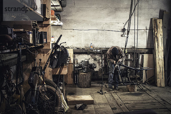 Mechaniker repariert demontiertes Oldtimer-Motorrad in der Werkstatt