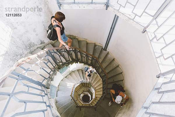 Hochwinkelaufnahme von drei jungen Erwachsenen  die eine Wendeltreppe hinuntergehen  Como  Lombardei  Italien
