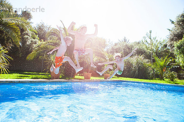 Vater und Söhne springen in der Luft in ein Freibad