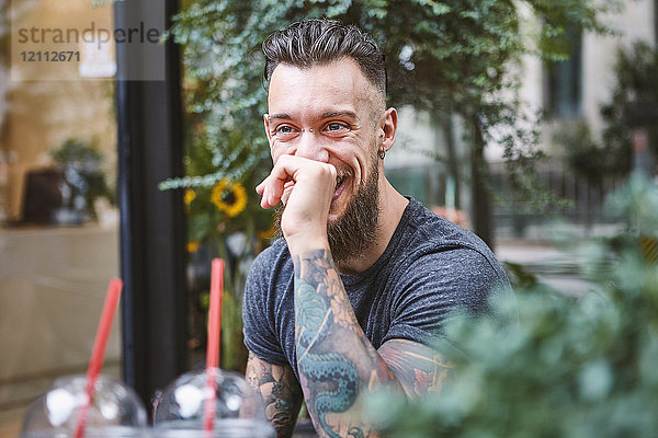 Junger männlicher Hipster lacht im Bürgersteig-Café  Shanghai Französische Konzession  Shanghai  China