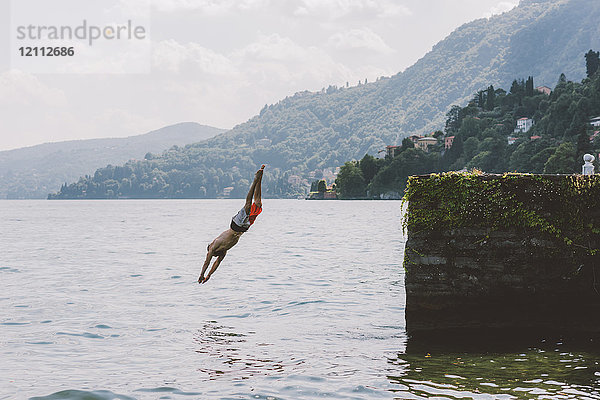 Junge männliche Schwimmer tauchen vom Pier  Comer See  Lombardei  Italien