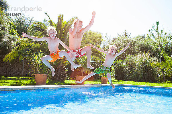 Vater und Söhne springen in der Luft in ein Freibad