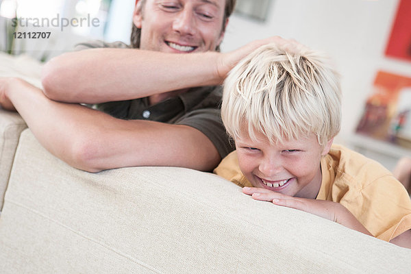 Vater und Sohn entspannen sich lächelnd auf dem Sofa