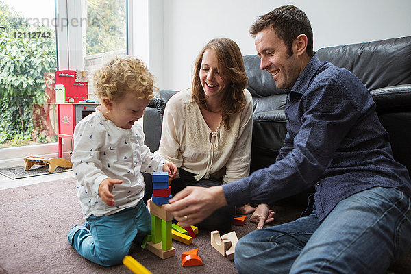 Eltern und Kleinkind spielen mit Bausteinen