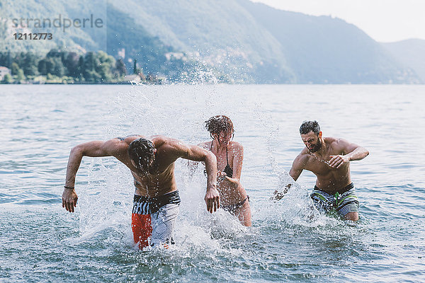 Drei junge erwachsene Freunde spielen im Comer See  Como  Lombardei  Italien
