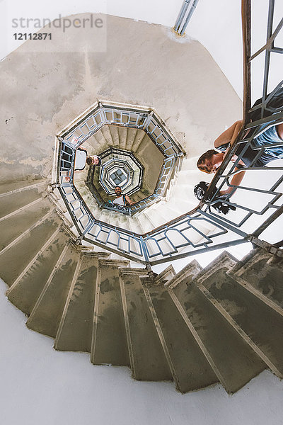 Niedrigwinkel-Porträt von drei jungen erwachsenen Freunden  die von einer Wendeltreppe nach unten blicken  Como  Lombardei  Italien